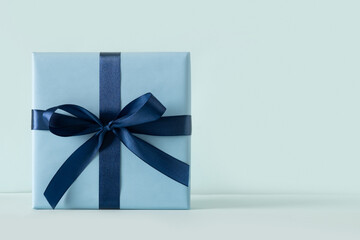 Blue gift box on pastel blue background. Birthday greeting card. Holiday present Close up. Copy space.