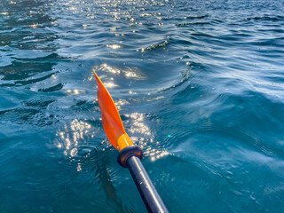 Paddle Water Kayaking - Close-up of a red and black paddle moving through turquoise water on a...