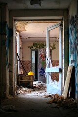 Broken doorway leading through an abandoned building with yellow helmet and scattered debris
