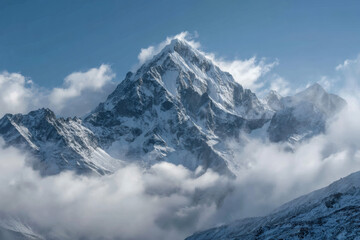 Obraz premium Majestic snow capped mountain peak piercing through soft white clouds under a clear blue sky