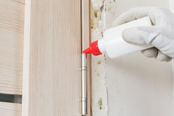 oil can with red cap, lubricating door hinge, close-up