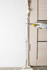 in the hand of the master, a sharp knife for cutting the mounting foam, from the doorway, after installation