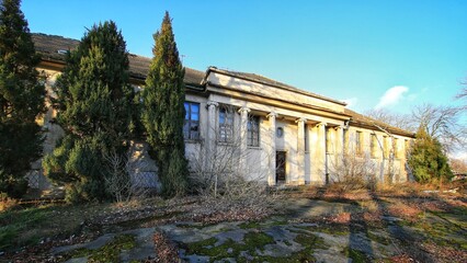 Abandoned neoclassical building in Schonebeck, Germany, with tall columns, broken windows, and...