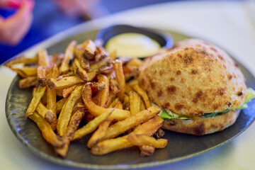 Homemade hamburger with fries and sauce on a plate with selective focus.