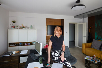a woman is leaning against a desk and studying some documents