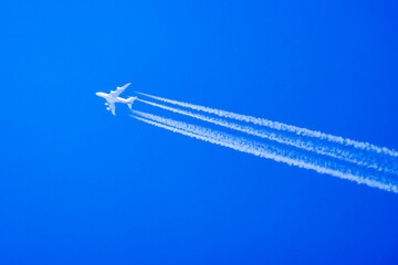a passenger plane in the blue sky leaving traces behind