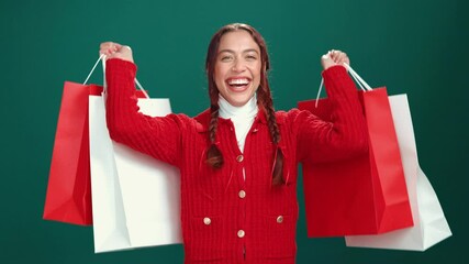 Christmas, face and happy woman dance with shopping bags for celebration or laugh. Xmas, portrait or excited shopaholic with gifts, presents or holiday discount for fashion on green studio background