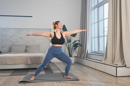 Yoga fitness workout training. Woman practicing yoga at home. Plus size female doing sports exercise on yoga mat indoor. Girl in sportswear have training workout for weight loss. Sport and fitness - Powered by Adobe