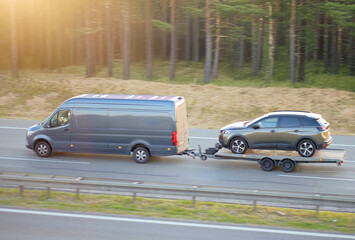 Fototapeta premium Utility Van Towing SUV on Car Trailer – Vehicle Transport on Highway