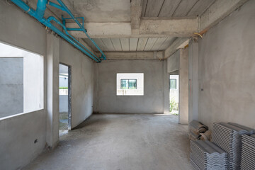 An empty interior of a building under construction showcase its modern design. The space feature concrete wall, visible plumbing, and open area illuminated by daylight.