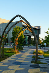 Contemporary public walkway with geometric pavement and arch structures outside modern architecture

