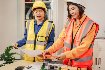Two female architects discussing an interior design project and drawing blueprints.