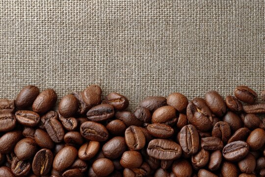 Roasted coffee beans arranged on coarse burlap filling the lower portion of the image