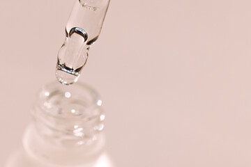 Extreme close-up of a glass pipette with a moisturizing serum with bubbles. Cosmetic products....