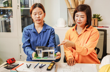 Two female architects discussing an interior design project and drawing blueprints.