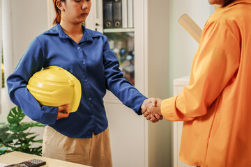 Two female architects discussing an interior design project and drawing blueprints.