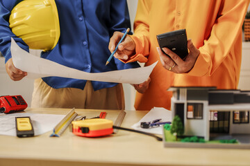 Two female architects discussing an interior design project and drawing blueprints.
