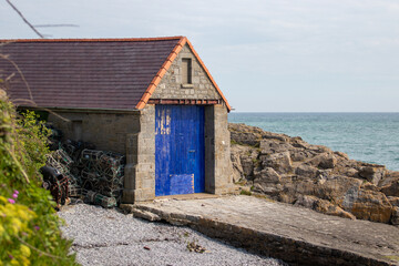 Boat house with blue painted door and sea in the distance