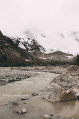 Landscape of a fast-flowing mountain river in a pine forest. Large stones in the river. Elbrus region