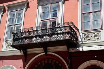 decorative wrought iron balcony and balustrade. old classic building facade and architecture. stucco elevation with wood windows and rich decoration. european architecture. travel and tourism concept