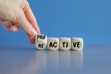 Businessman hand turns cubes and changes the word reactive to proactive. Beautiful blue background,...