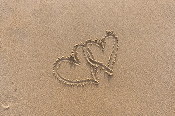 Pair Of Hearts Drawn On Sand Textured Background