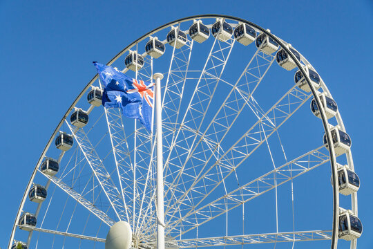 An Australian flag flying in front of a large ferris wheel