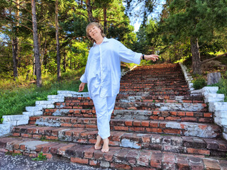 Middle-aged blonde woman enjoying a carefree moment strolling down rustic steps surrounded by...