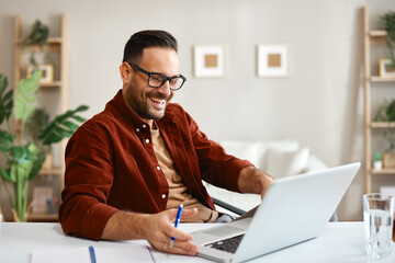 Freelancer smiling and working from home using laptop