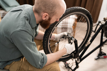 bicycle repair, care and maintenance concept. Bearded man repairing bicycle fixing bike wheel on...