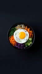 Delicious bibimbap korean rice dish recipe with fried egg and fresh vegetables on dark background