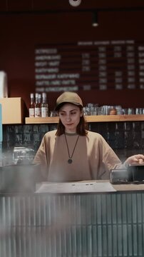 girl cashier works behind the bar at a city coffee