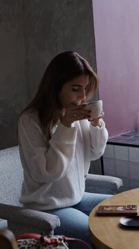 cute girl sits at a coffee shop table and surfs