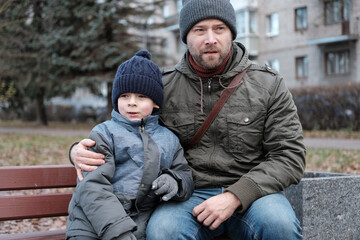 Father and son walking down on sidewalk together. Portrait of a handsome middle-aged man with...
