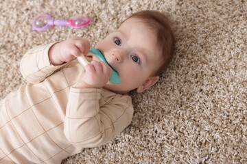 Cute little baby with rattle toy on floor at home, above view