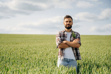 Standing with arms crossed. Man farmer is on the agricultural field