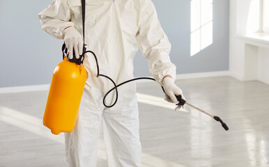 Exterminator service man, worker wearing protective white coverall holding pump sprayer chemicals,...