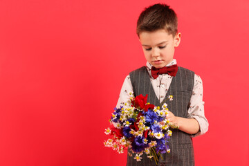 Cute little boy with bouquet of beautiful flowers on red background. Space for text