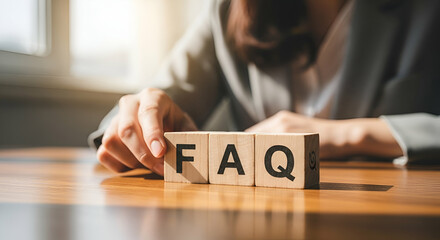 Businesswoman Adjusting Wooden Blocks Spelling FAQ for Frequently Asked Questions on Desk in Office Environment with Natural Light