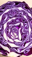 Obraz premium Close-up cross-section of purple cabbage showing intricate geometric pattern of leaves, isolated on light beige background, vibrant vegetable macro photography, fresh produce detail