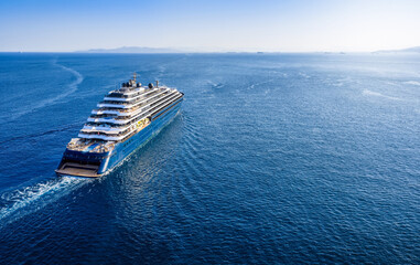 Aerial rear view of a modern luxury cruise ship or yacht sailing with speed over calm ocean with...