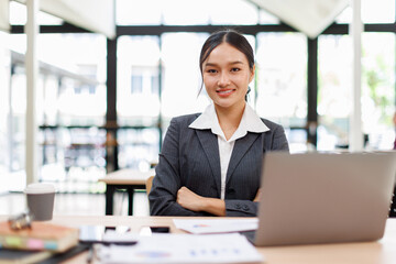 Young asian business woman sitting at the office and using laptops for document work. Confident professional female wearing business casual
