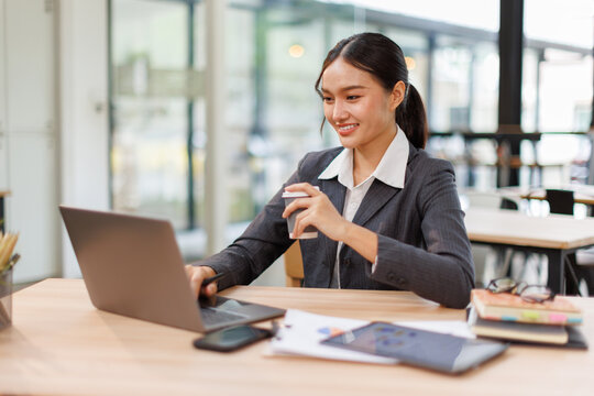 Asian business woman accounting holding coffee cup using calculating income-expenditure and analyzing real estate investment data report Financial and tax systems concept.	