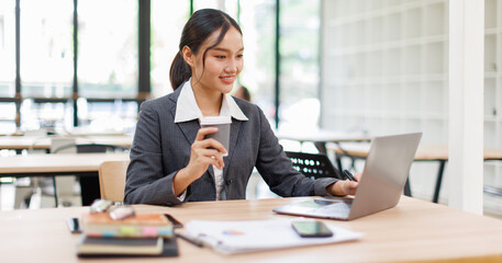 Asian business woman accounting holding coffee cup using calculating income-expenditure and...