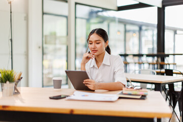 Fototapeta premium Young asian business woman manager accounting analyst checking bills, analyzing sales statistics management, taxes financial data documents or marketing report papers working in office using laptop. 