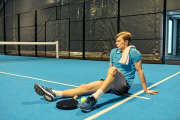 Young athlete resting on padel court after an intense match