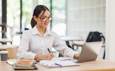 Attractive asian young confident businesswoman Accounting using calculating income-expenditure and...