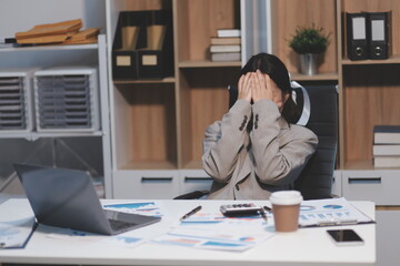 Young Asian woman feeling migraine head strain. Tired, Overworked businesswoman financier while...