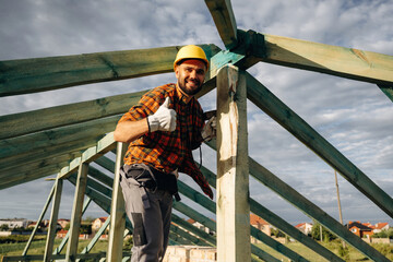 Unfinished place, under sunlight. Construction worker is on the roof of a house