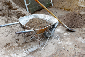 Rusty wheelbarrow filled with sand and dirt at construction site
